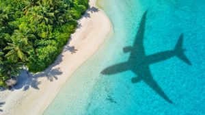 Travel concept with airplane shadow and tropical beach. Tropical paradise and beach holiday conceptual image.