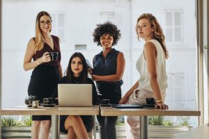 Portrait of four successful young businesswomen together in office. Group of multi-ethnic businesswomen looking at camera.