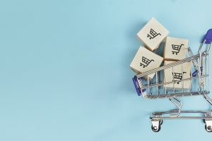 Boxes in a shopping cart on blue background. Concept: online shopping, e commerce and delivery of goods. Copy space