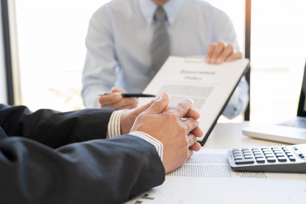 Confident insurance agent broker man holding document and present pointing showing an insurance policy contract form to client Business Communication Connection Concept