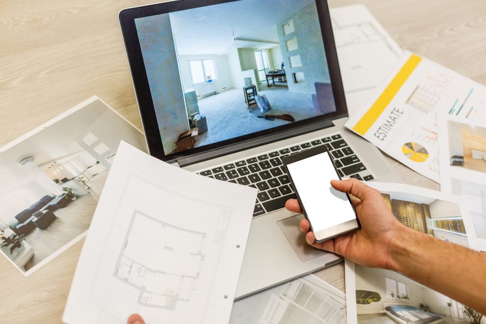 Construction engineer and architect's desk with house projects, laptop, tools and wood swatches top view, male hands drawing